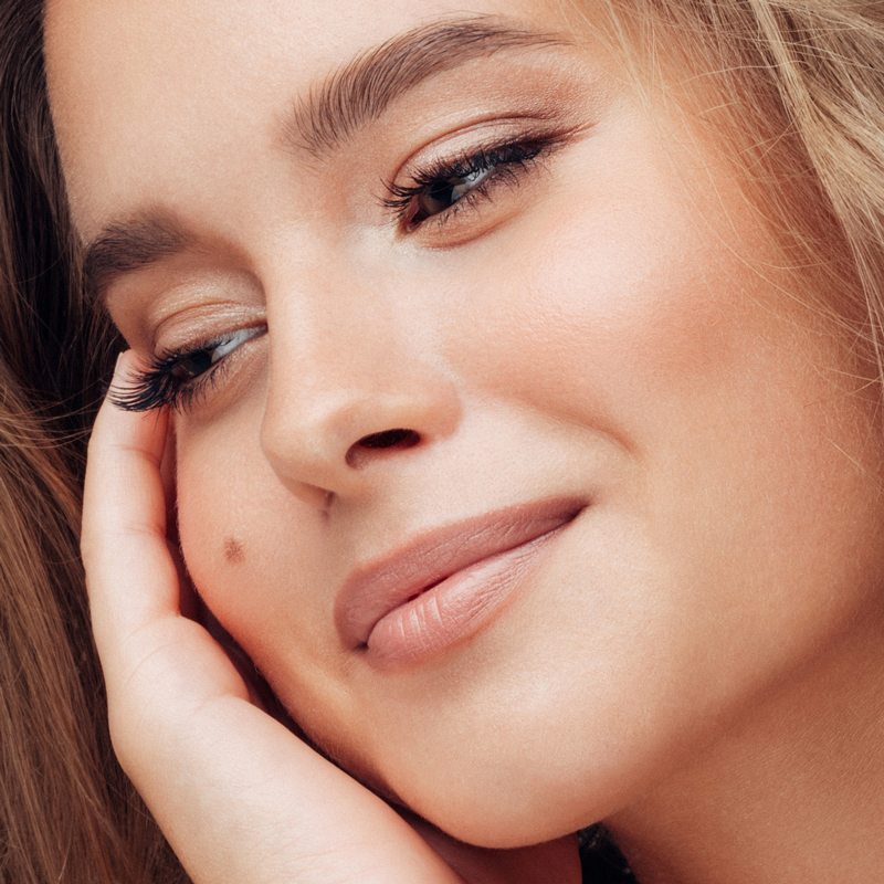 Woman with clear skin resting her face against her hand.