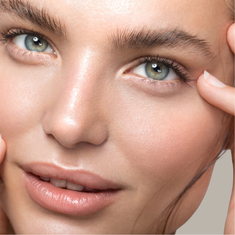 Woman with glowing skin gently touching her face.